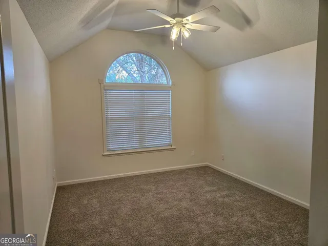 an empty room with windows and fan