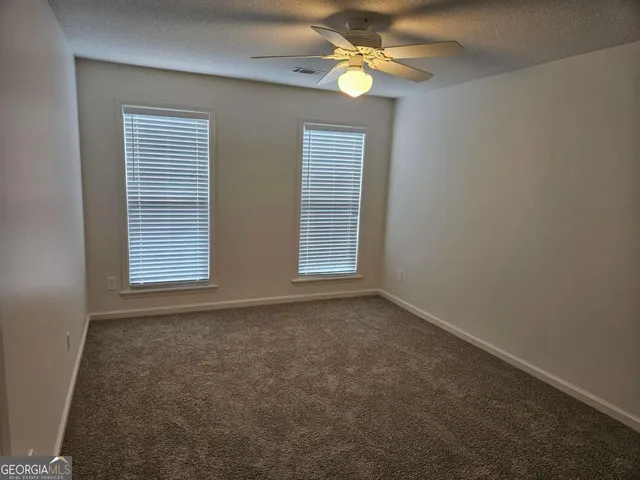 an empty room with a chandelier fan and windows