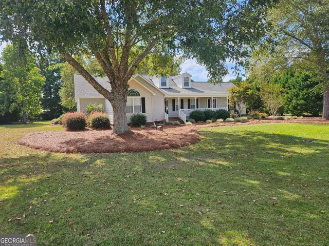 a front view of a house with a garden and trees