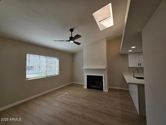 an empty room with windows a fireplace and a chandelier fan