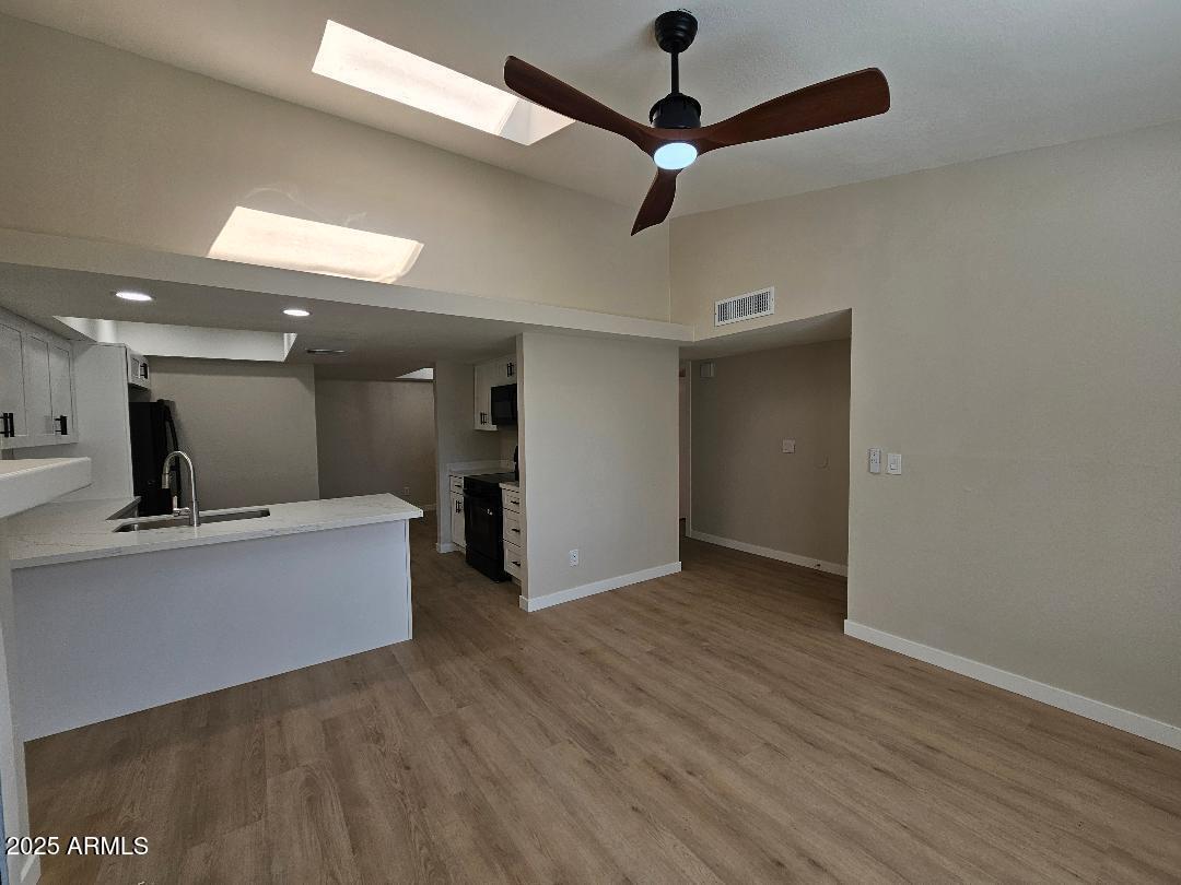 2020 West Union Hills Drive, Unit 116 Phoenix, AZ 85027 - Photo 5 of 28 an empty room with wooden floor a ceiling fan and kitchen view