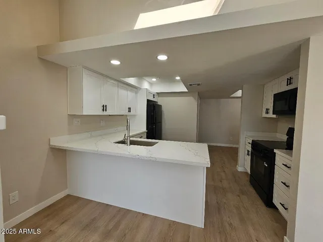 a kitchen with a sink a refrigerator and white cabinets