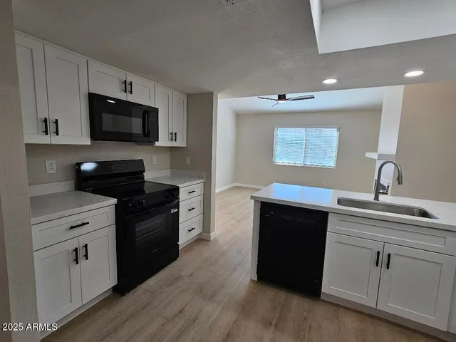 a kitchen with a sink stainless steel appliances and wooden floor