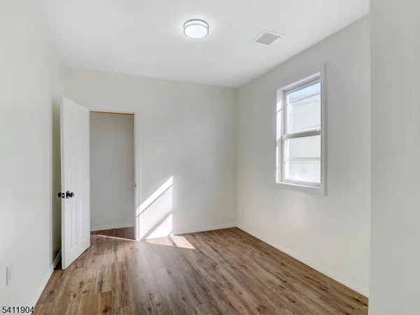 an empty room with wooden floor cabinet and windows