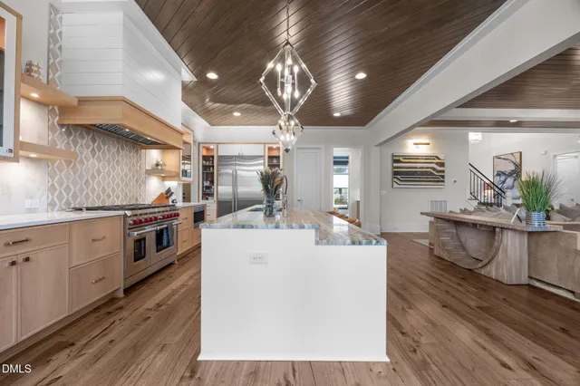 a large kitchen with stainless steel appliances kitchen island a large counter top a stove and a wooden floors