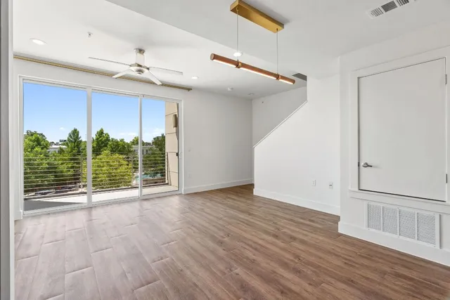 an empty room with wooden floor fan and windows