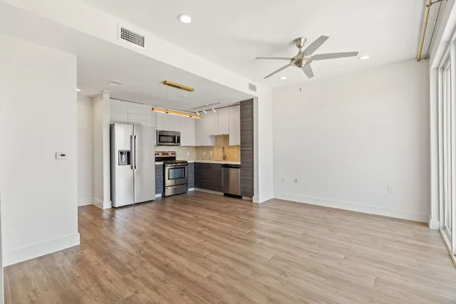 a view of a kitchen with wooden floor a sink and a refrigerator