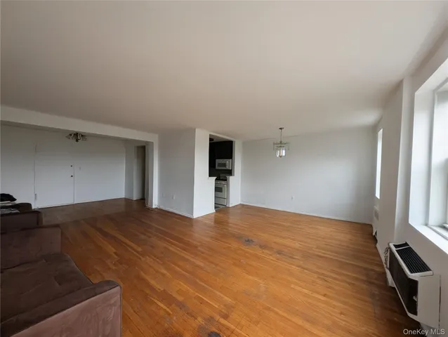 a view of an empty room with window and wooden floor