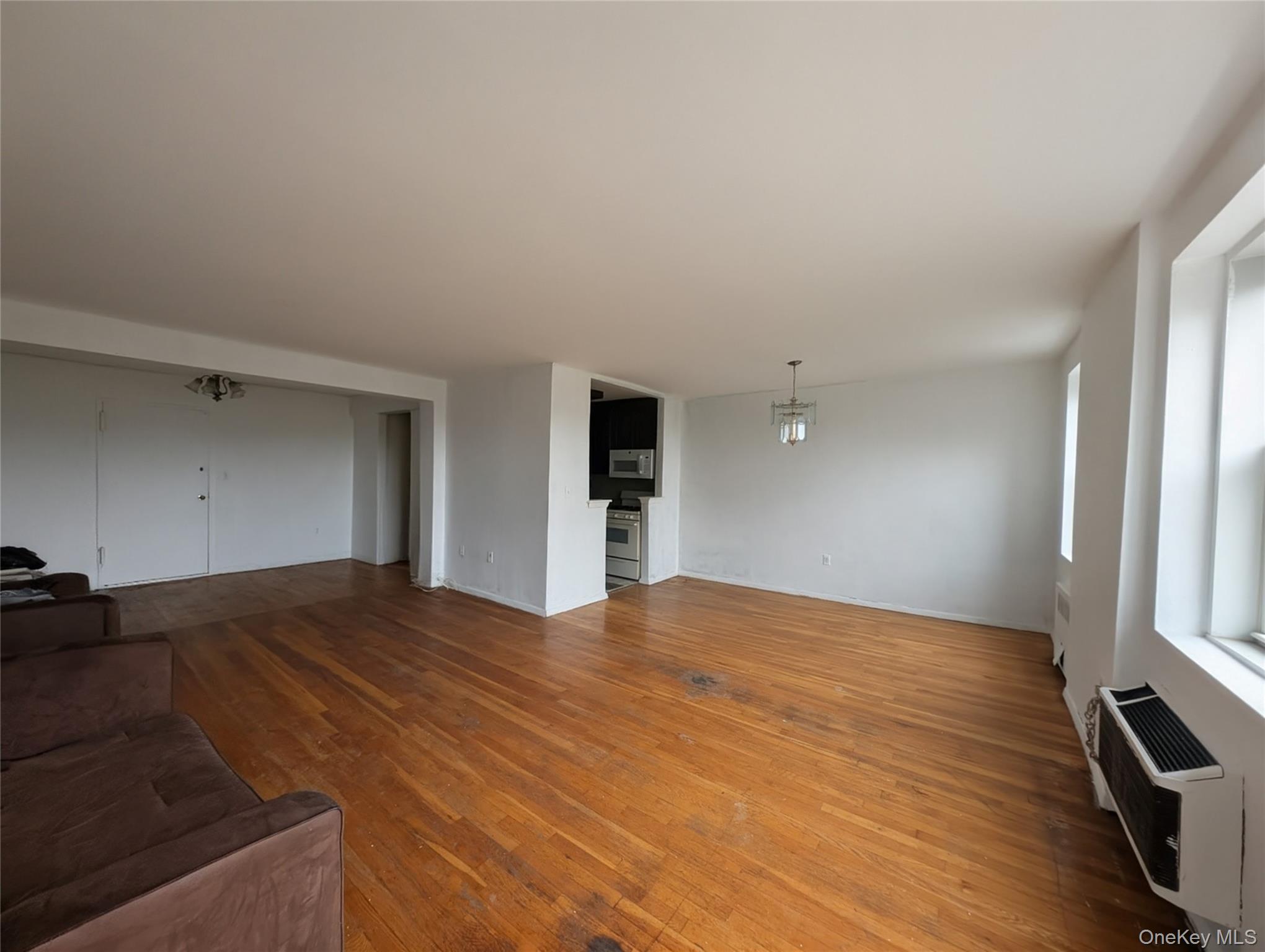 a view of an empty room with window and wooden floor