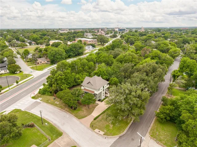 an aerial view of residential houses with outdoor space and trees