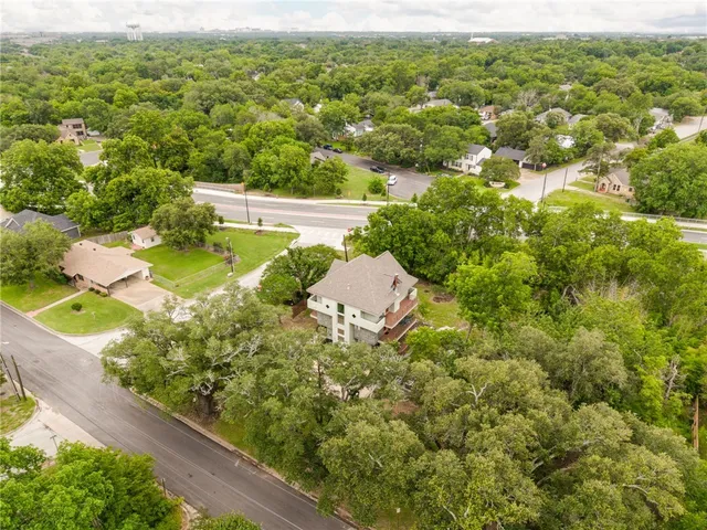a view of a house with a yard and large trees