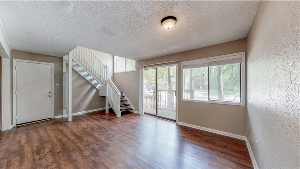 a view of an empty room with stairs and hardwood floor