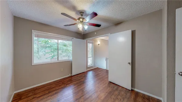 an empty room with wooden floor fan and windows