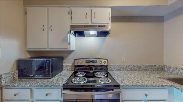 a kitchen with granite countertop white cabinets and a stove with granite countertop