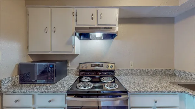 a kitchen with granite countertop white cabinets and a stove with granite countertop