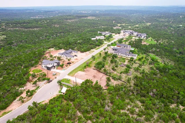 an aerial view of residential houses with outdoor space and trees