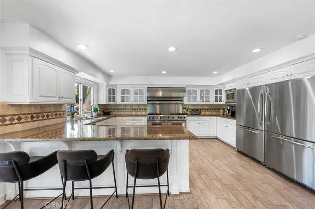a kitchen with stainless steel appliances granite countertop a refrigerator and a stove top oven