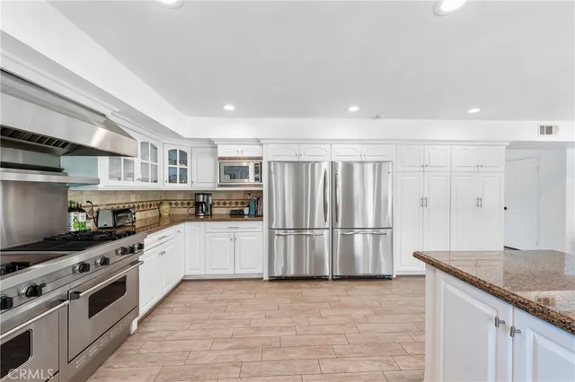 a kitchen with stainless steel appliances white cabinets and wooden floor
