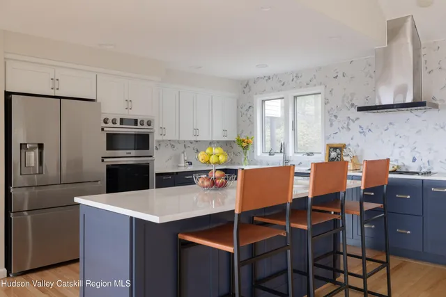 a kitchen with stainless steel appliances kitchen island granite countertop a table chairs and a refrigerator