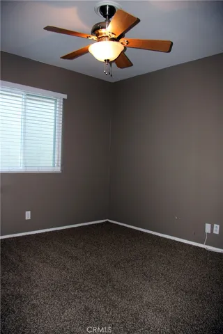 an empty room with a window and a fan