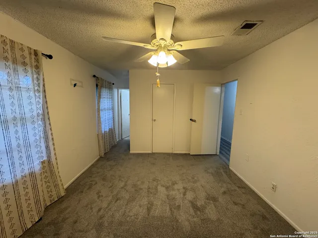 a view of an empty room with a chandelier fan