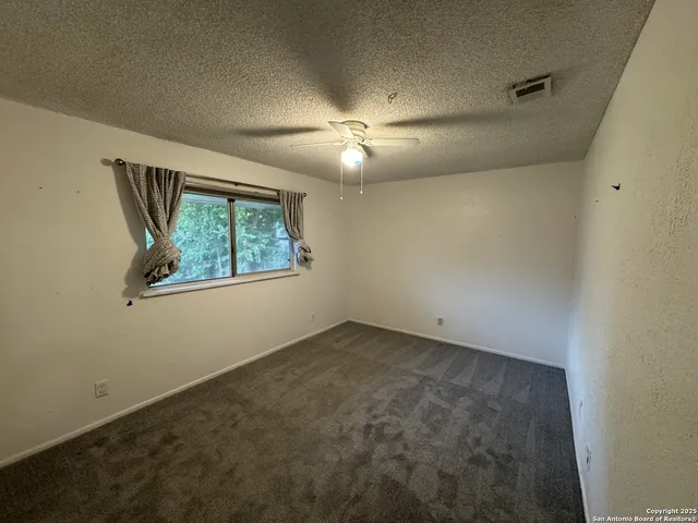 an empty room with windows and fan
