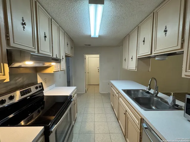 a kitchen with stainless steel appliances a sink dishwasher a stove a refrigerator and cabinets