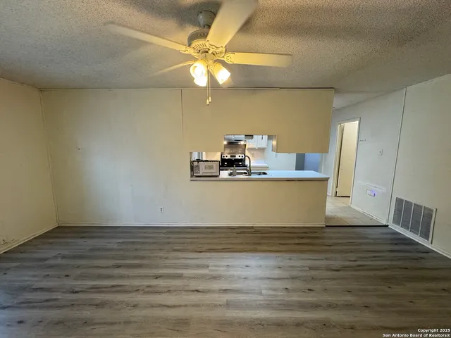 a view of a room with wooden floor and ceiling fan
