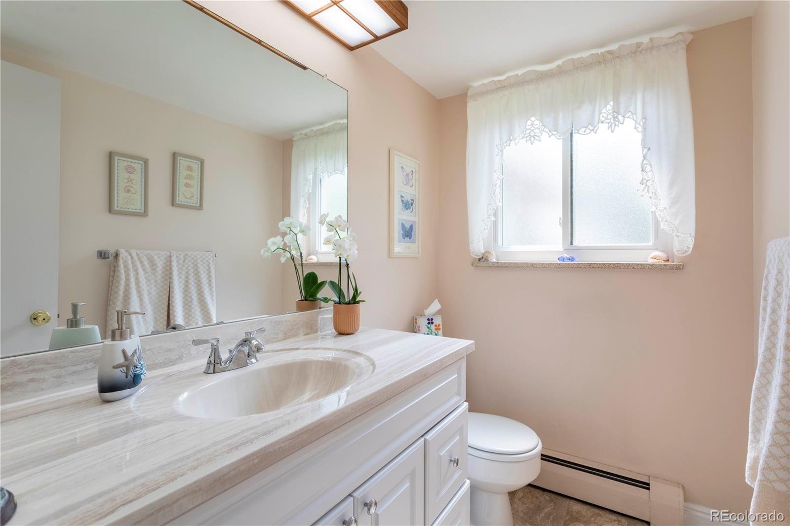 6001 Welch Street Arvada, CO 80004 - Photo 12 of 32 a bathroom with a granite countertop toilet a sink and mirror