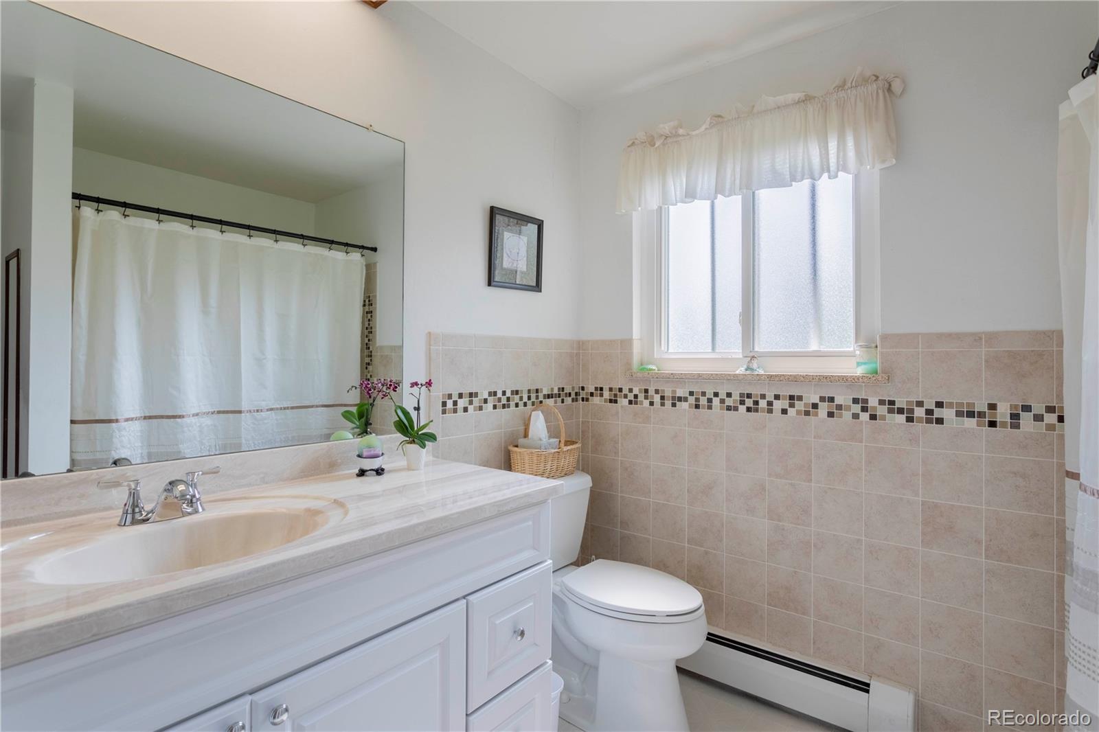 6001 Welch Street Arvada, CO 80004 - Photo 13 of 32 a bathroom with a sink a toilet and a mirror