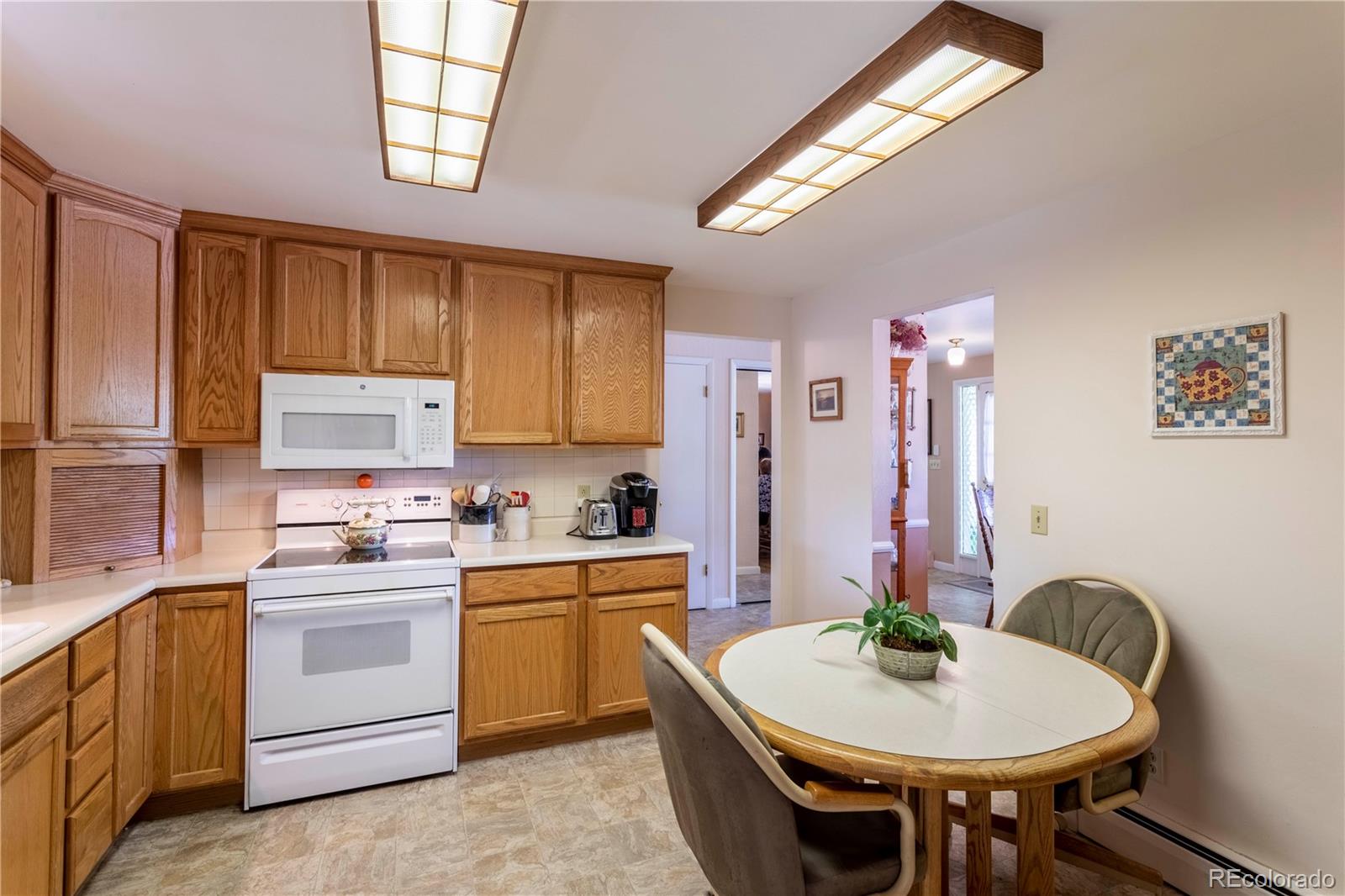 6001 Welch Street Arvada, CO 80004 - Photo 10 of 32 a kitchen with stainless steel appliances a white table chairs and a refrigerator