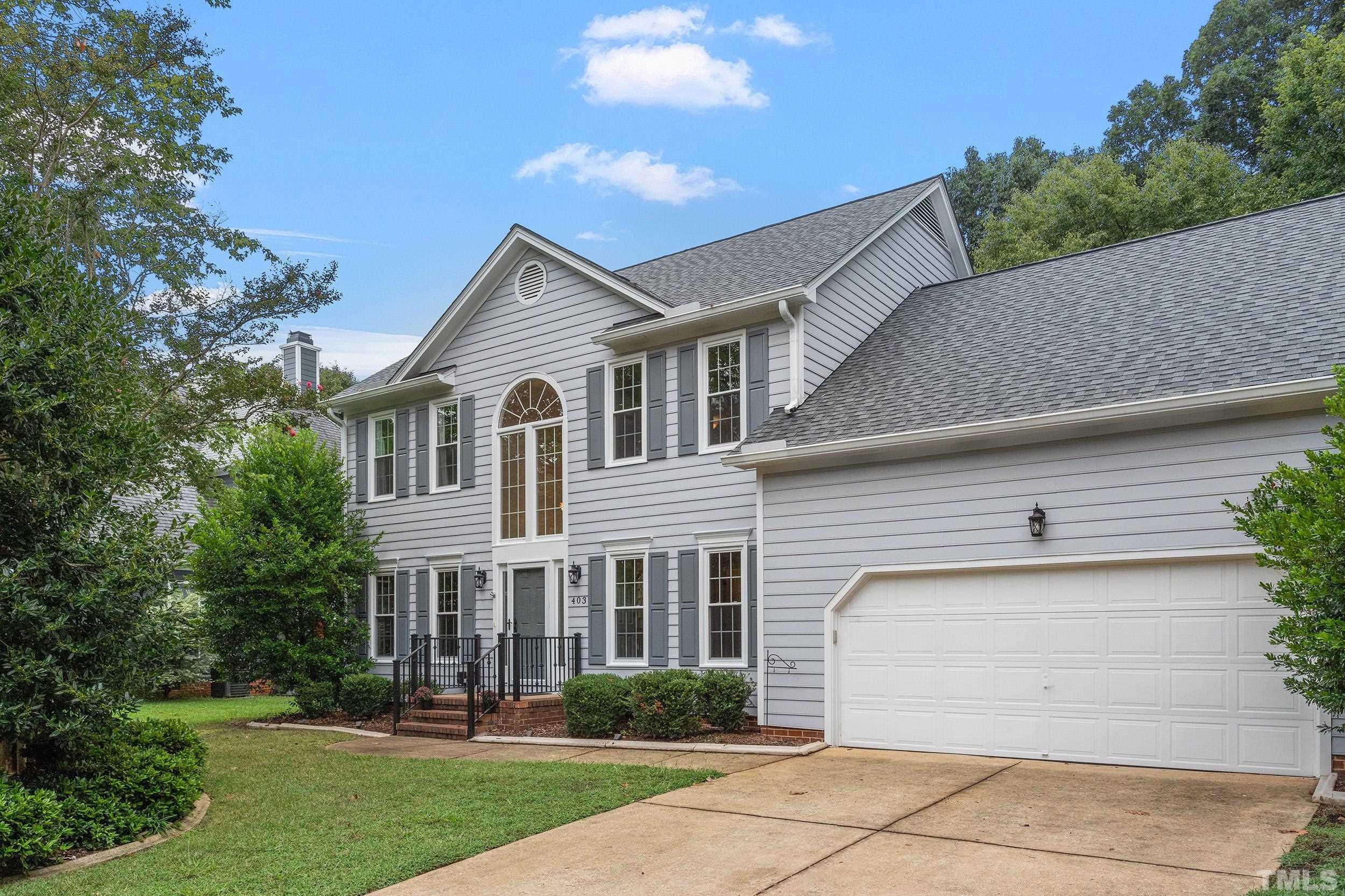 a view of a white house next to a yard and large trees