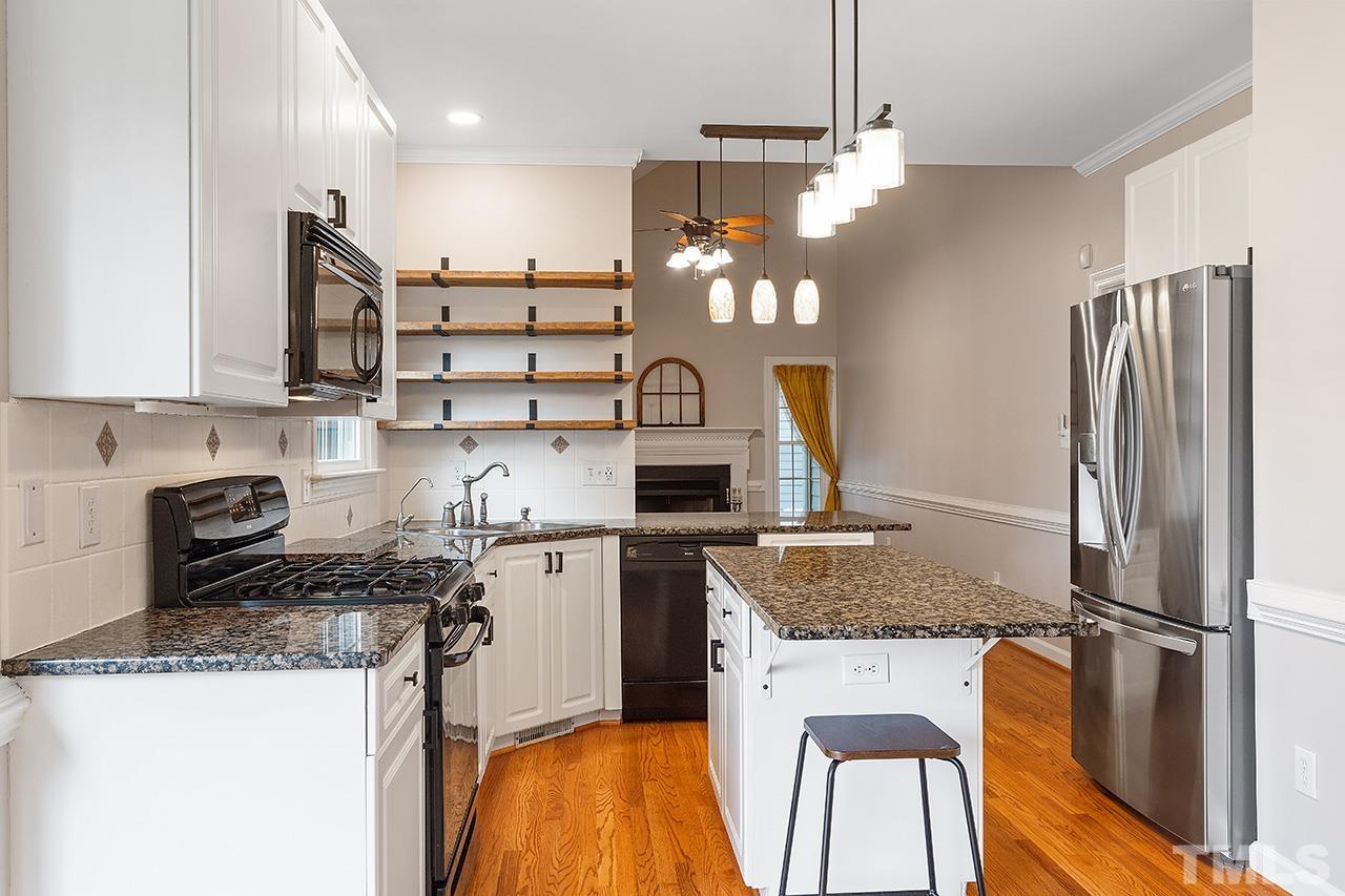 403 Danton Drive Cary, NC 27518 - Photo 8 of 38 a kitchen with kitchen island granite countertop wooden cabinets and refrigerator