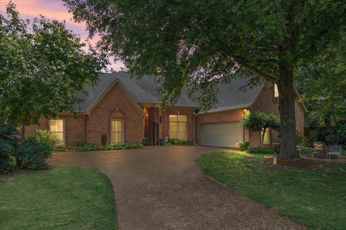 View of front facade featuring brick siding, driveway, a shingled roof, and a yard