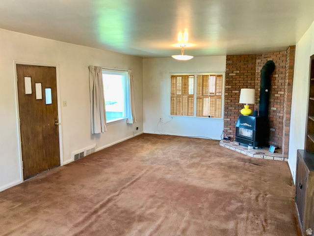 630 North Main Street Monroe, UT 84754 - Photo 12 of 63 Unfurnished living room featuring a wood stove and carpet