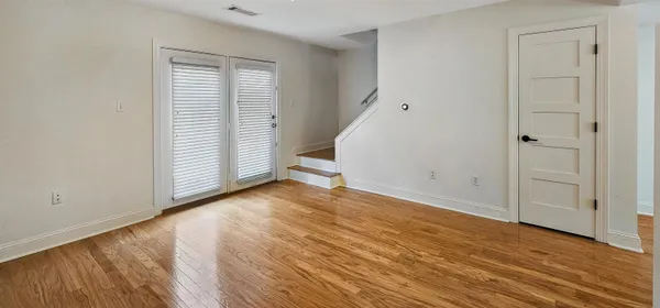 an empty room with wooden floor and windows