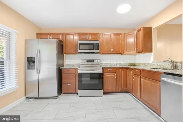 a kitchen with granite countertop a refrigerator and a stove top oven
