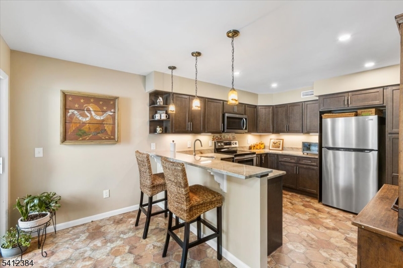 10 Gristmill Sparta, NJ 07871 - Photo 13 of 35 a kitchen with stainless steel appliances a stove a refrigerator a sink a dining table and chairs with wooden floor
