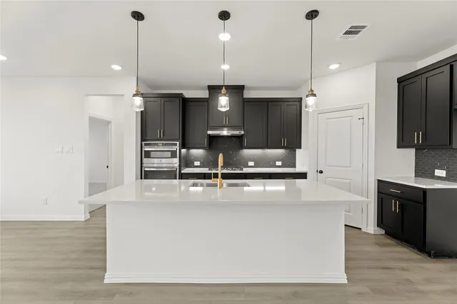 a large kitchen with kitchen island a large counter top stainless steel appliances and cabinets