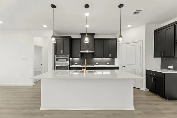 a large kitchen with kitchen island a large counter top stainless steel appliances and cabinets