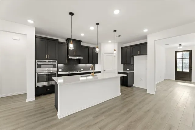 a kitchen with stainless steel appliances kitchen island wooden cabinets and wooden floor