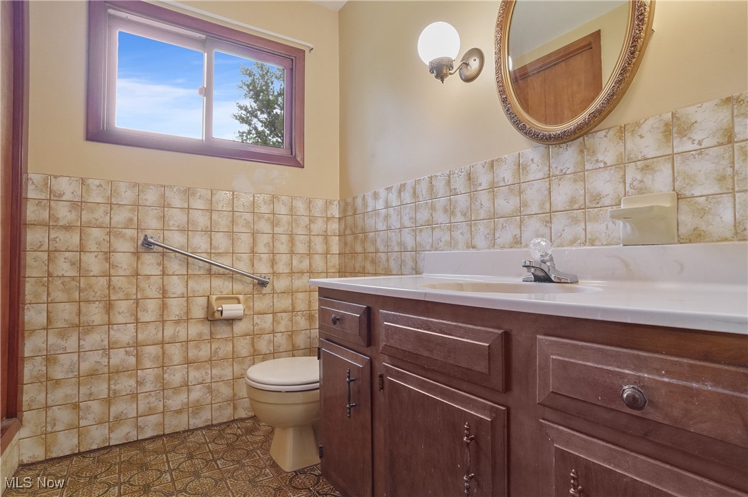 12395 Carter Road Painesville, OH 44077 - Photo 28 of 39 Bathroom with tile walls, toilet, vanity, tile patterned floors, and wainscoting