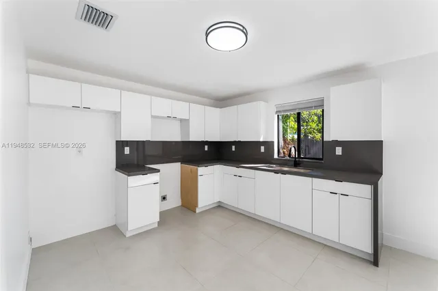 a large white kitchen with a stove a sink and dishwasher with white cabinets
