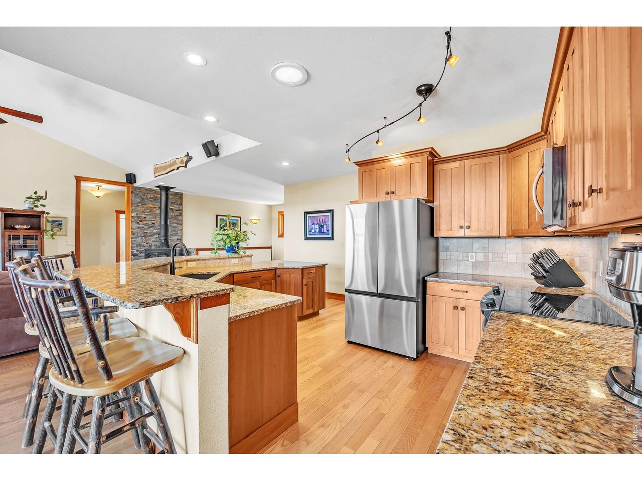 3237 Romnes Road Fort Garland, CO 81133 - Photo 13 of 42 a kitchen with stainless steel appliances kitchen island granite countertop a refrigerator a stove top oven and a dining table with wooden floor