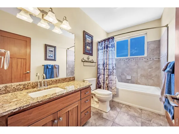 a bathroom with a granite countertop sink toilet mirror and bathtub