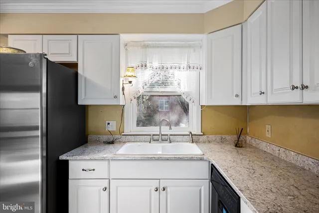 a kitchen with granite countertop white cabinets white stainless steel appliances with a sink and dishwasher