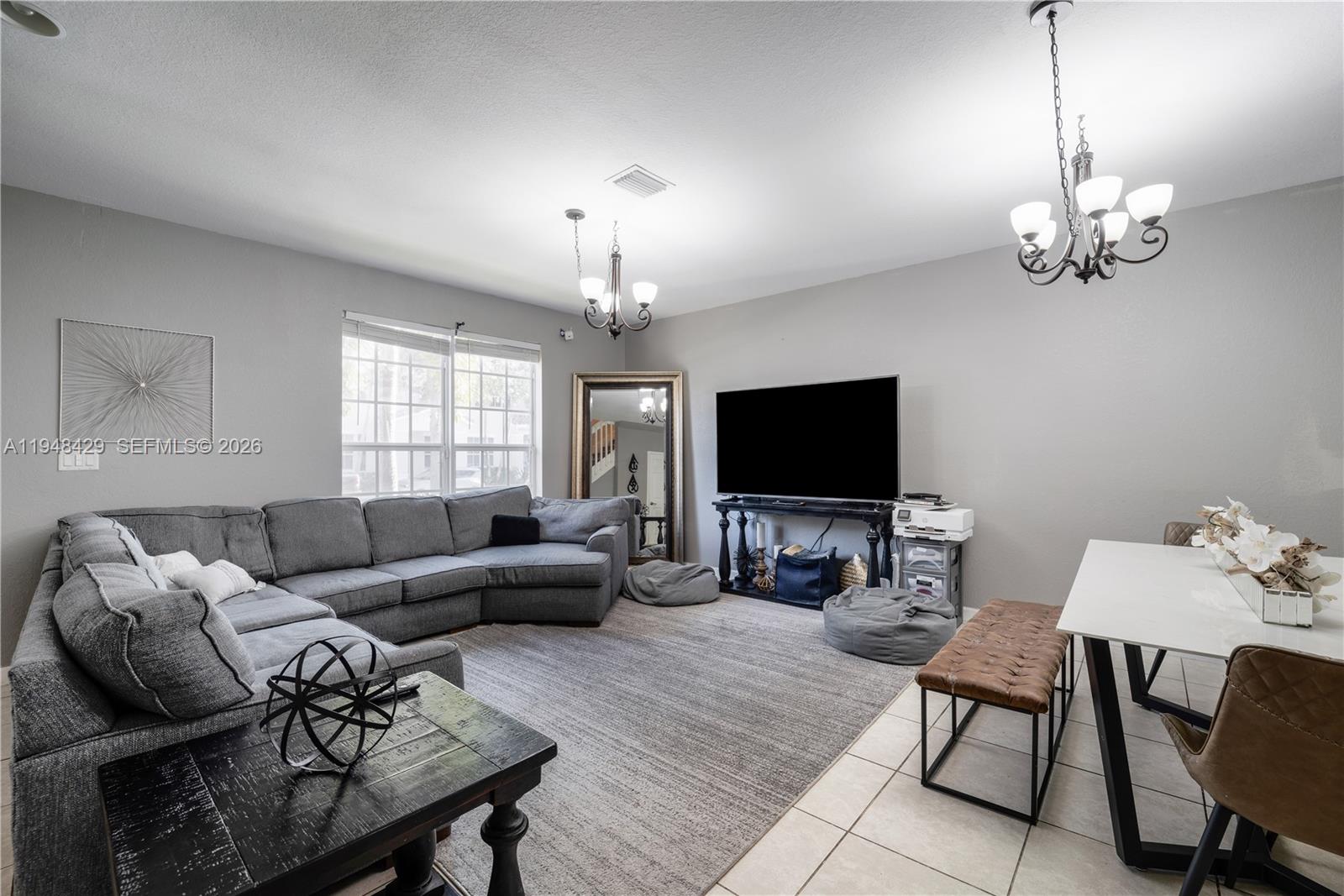 9360 Southwest 171st Court Miami, FL 33196 - Photo 6 of 43 a living room with furniture a chandelier and a flat screen tv