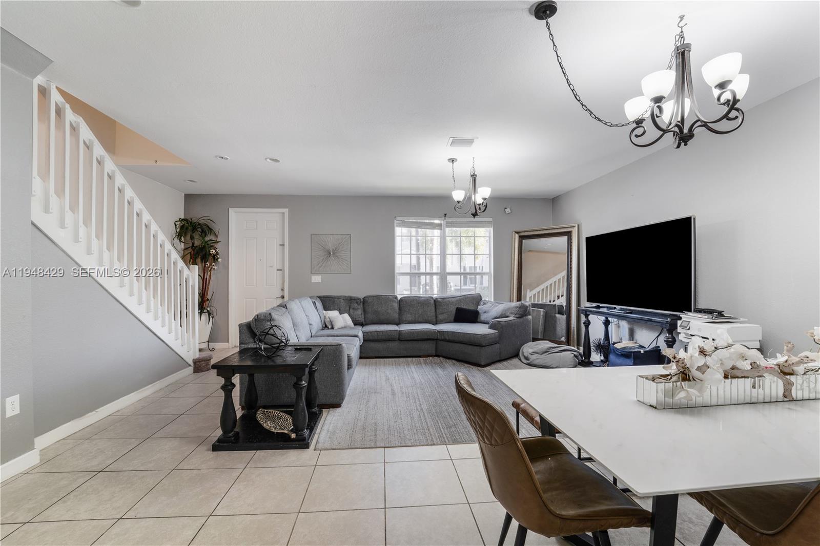 9360 Southwest 171st Court Miami, FL 33196 - Photo 8 of 43 a living room with furniture a chandelier and a flat screen tv