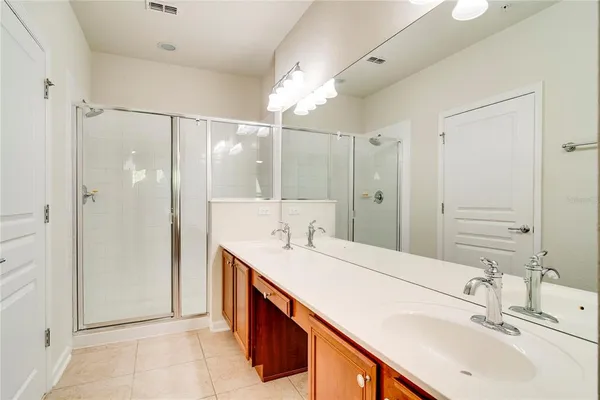 a bathroom with a double vanity sink mirror and shower