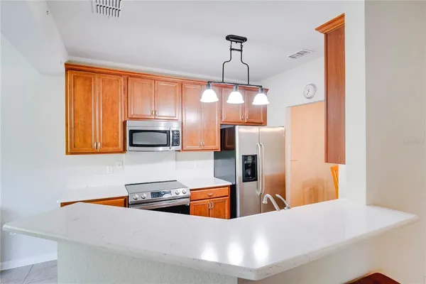 a kitchen with stainless steel appliances a sink a stove a refrigerator cabinets and a window